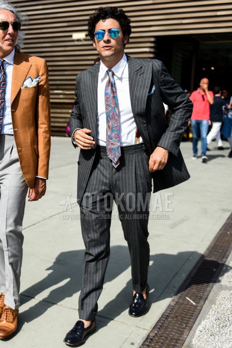 Spring and fall men's coordinate outfit with plain gold sunglasses, plain white shirt, black tassel loafer leather shoes, dark gray striped suit, and multi-colored other tie.