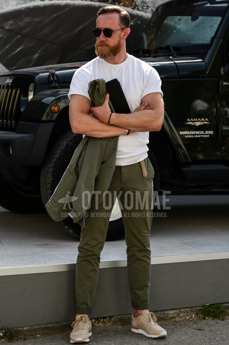 A summer men's coordinate outfit with plain sunglasses, a plain white T-shirt, plain olive green chinos, and beige low-cut sneakers.