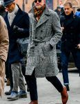 Men's fall/winter outfit with plain beige sunglasses, multi-colored other scarf/stall, glen check gray checked belted coat, plain navy slacks, and brown chukka boots.