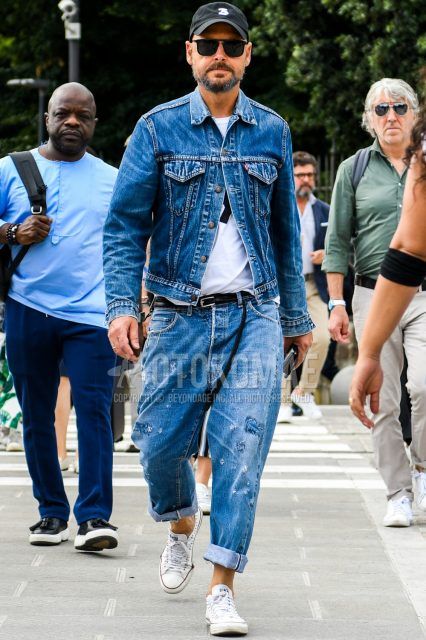 Men's coordinate and outfit with one-pointed baseball cap, solid color sunglasses, solid color blue denim jacket, solid color white t-shirt, solid color black leather belt, solid color blue denim/jeans, and Converse All Star white low-cut sneakers.