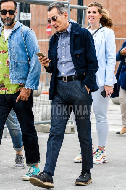 Men's coordinate and outfit with solid color sunglasses, solid color navy M-65, solid color blue shirt, solid color black leather belt, solid color navy denim/jeans and black work boots.