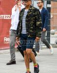 Men's coordinate and outfit with plain glasses, multi-colored camouflage tailored jacket, white striped t-shirt, plain navy shorts, multi-colored socks socks, and black coin loafer leather shoes.