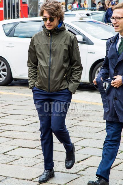 Men's coordinate and outfit with plain sunglasses, olive green solid color windbreaker, navy solid color slacks, and black coin loafer leather shoes.