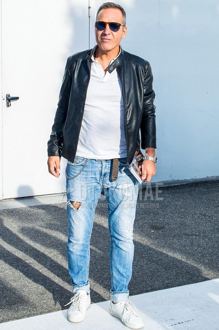 A spring and fall men's coordinate outfit with plain sunglasses, a plain black rider's jacket, a plain white T-shirt with a henley neck, a plain leather belt, plain blue damaged jeans, and white low-cut sneakers.