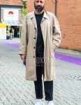 A men's fall/winter outfit with a plain beige stainless steel collar coat, a plain black T-shirt, plain black chinos, and white low-cut sneakers.