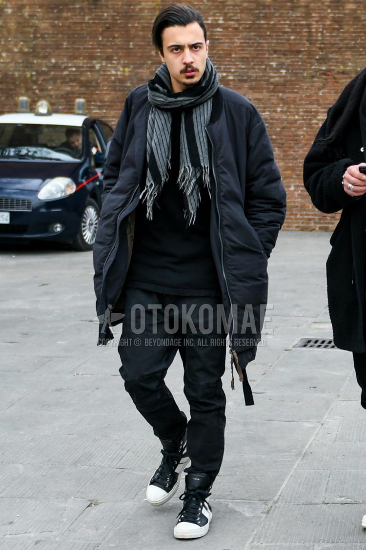 Men's coordinate and outfit with gray striped scarf/stall, solid black down jacket, solid black sweatshirt, solid black cotton pants, and black/white high-cut sneakers.