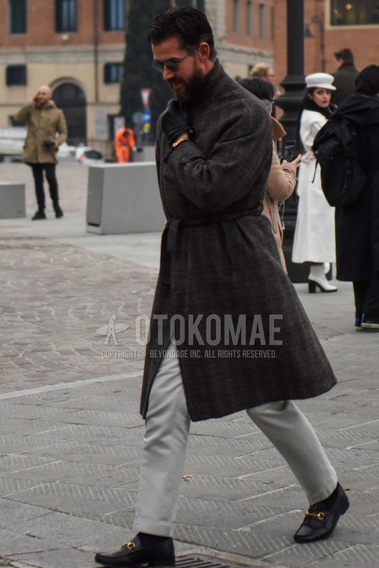 Men's coordinate and outfit with plain sunglasses, brown/dark gray checked belted coat, plain gray ankle pants, and black bit loafer leather shoes.