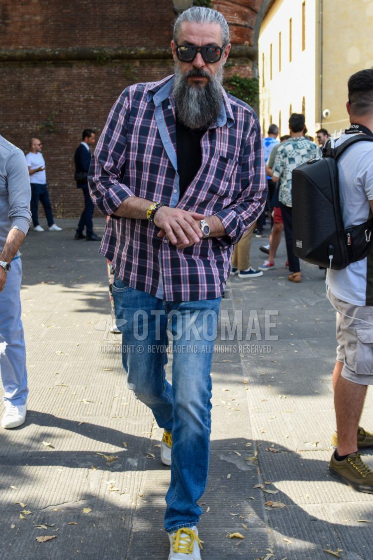 Men's coordinate and outfit with plain black sunglasses, navy/red checked shirt, plain navy t-shirt, plain blue denim/jeans, and white low-cut sneakers.