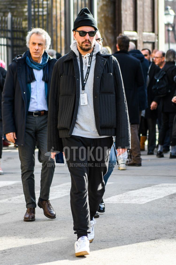 Men's coordinate and outfit with plain black knit cap, plain sunglasses, plain black outerwear, plain gray hoodie, plain black sweatpants, and white low-cut Adidas sneakers.