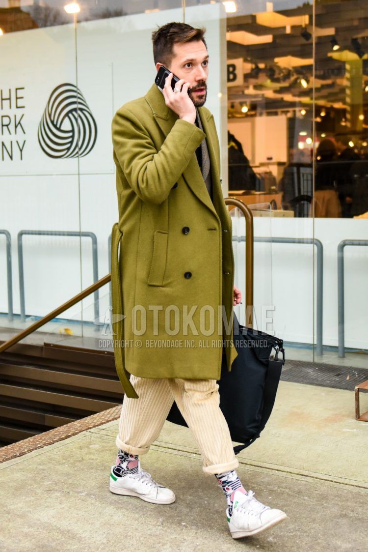 Olive green solid color belted coat, gray/beige checked tailored jacket, beige solid color winter pants (corduroy,velour), multi-colored socks, Adidas Stan Smith white low cut sneakers, black solid color briefcase/handbag. Men's coordinate/outfit with.