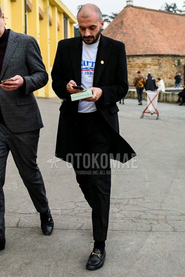 Men's coordinate and outfit with plain black chester coat, white decal logo T-shirt, plain black slacks, plain black socks, and Gucci black bit loafer leather shoes.