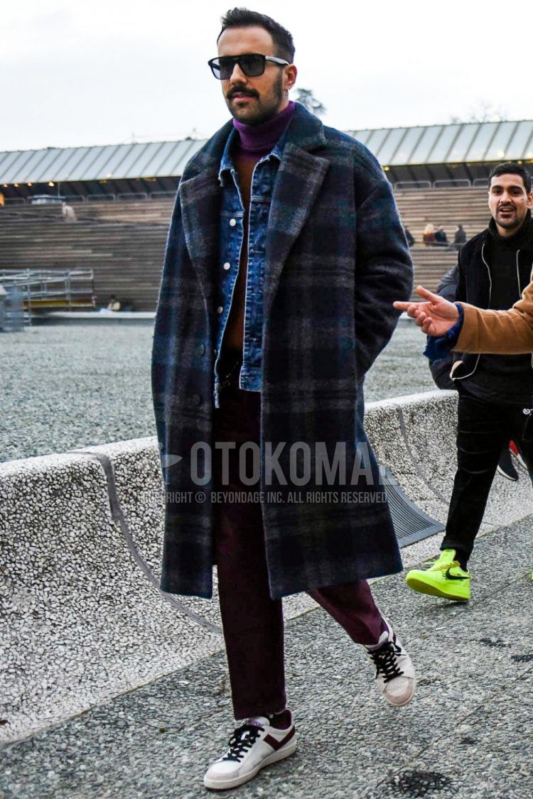 Men's coordinate and outfit with solid color sunglasses, gray checked chester coat, solid color blue denim jacket, solid color purple/beige turtleneck knit, solid color purple slacks, and white low-cut sneakers.