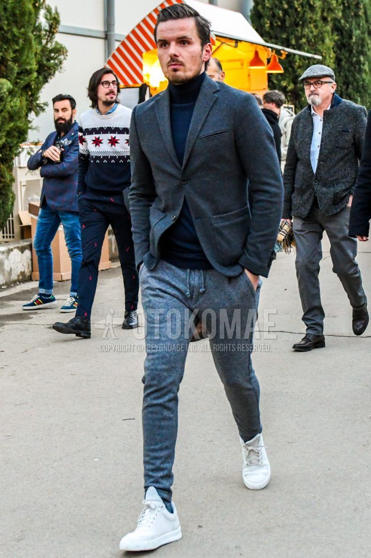 Men's coordinate and outfit with dark gray solid color tailored jacket, navy solid color turtleneck knit, gray solid color sweatpants, gray solid color socks, and white low-cut sneakers.