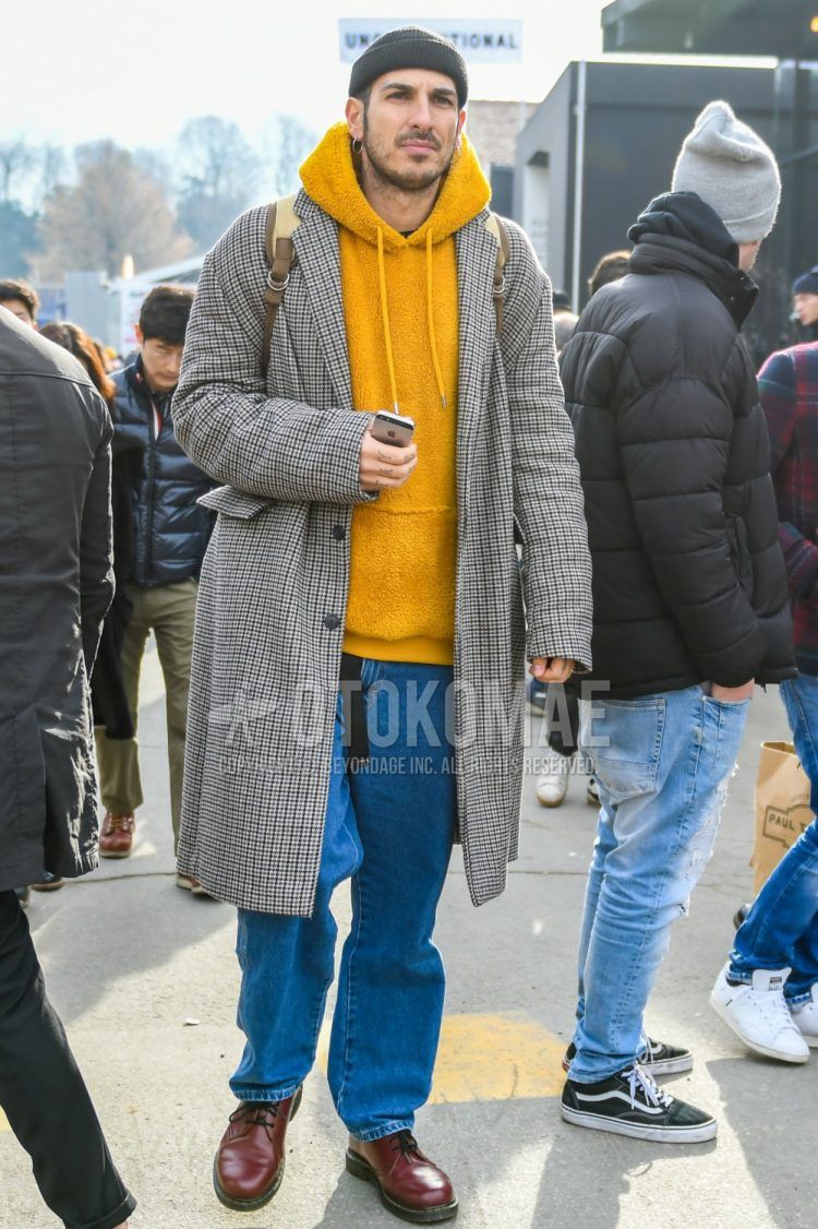 Men's coordinate and outfit with plain black knit cap, multi-colored checked chester coat, plain yellow hoodie, plain blue denim/jeans, and Dr. Martens brown plain toe leather shoes.