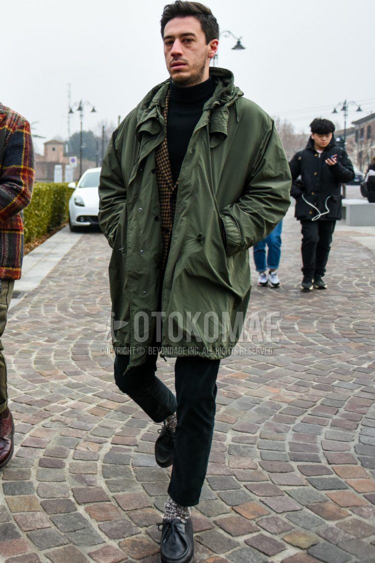 Men's coordinate and outfit with plain olive green mod coat, brown checked tailored jacket, plain black turtleneck knit, plain black denim/jeans, white and brown socks, and black leather shoes.