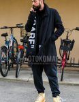 Men's coordinate and outfit with black graphic scarf/stall, solid black outerwear, solid black sweater, solid black sweatpants, and Nike orange high-cut sneakers.