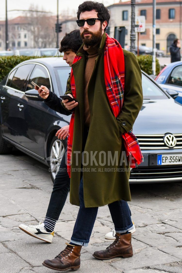 Men's coordinate and outfit with solid color sunglasses, red checked scarf/stall, olive green solid color chester coat, brown solid color turtleneck knit, navy solid color denim/jeans, navy solid color socks, and brown boots.