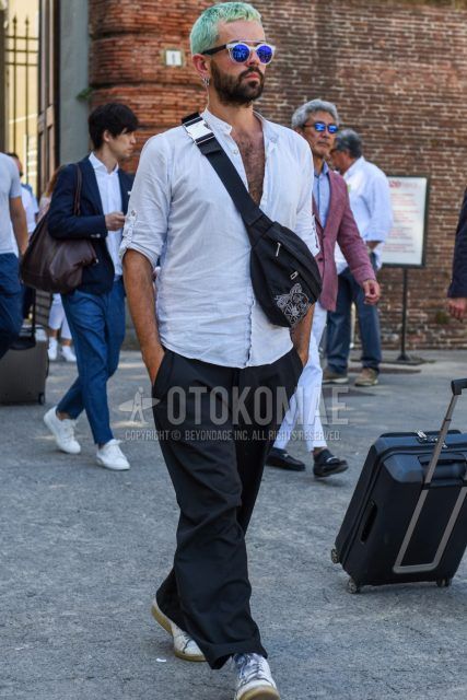 Men's coordinate and outfit with clear blue solid color sunglasses, solid color white shirt, solid color black wide pants, white low-cut sneakers, and black solid color body bag from Kenzo.