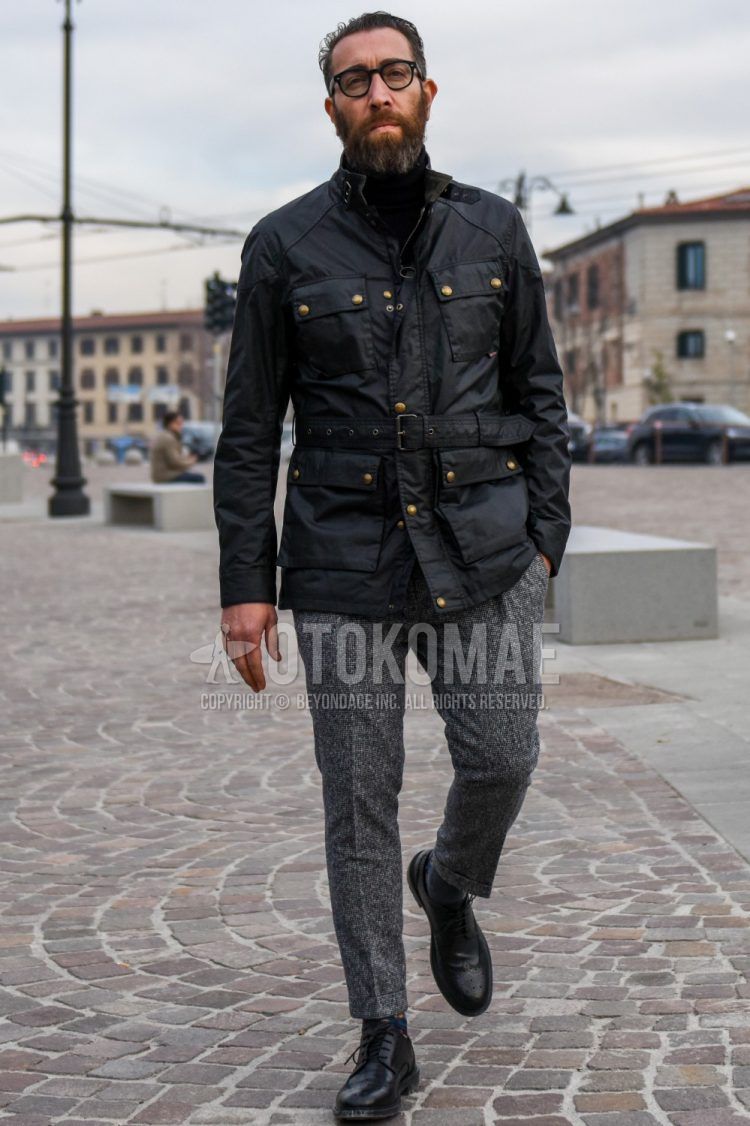 Men's coordinate and outfit with plain glasses, plain black field jacket/hunting jacket, plain black turtleneck knit, gray bottom slacks, multi-colored socks socks, black plain toe leather shoes.