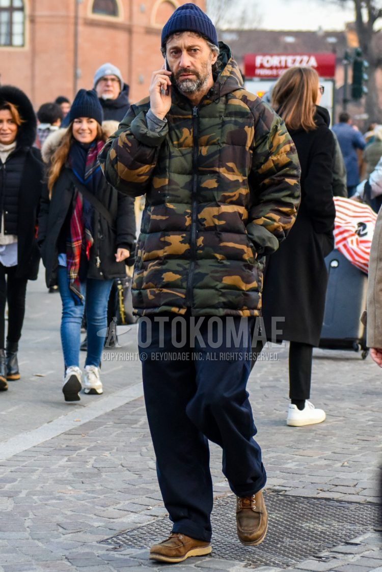 Men's coordinate and outfit with plain navy knit cap, olive green camouflage down jacket, plain navy chinos and beige work boots.