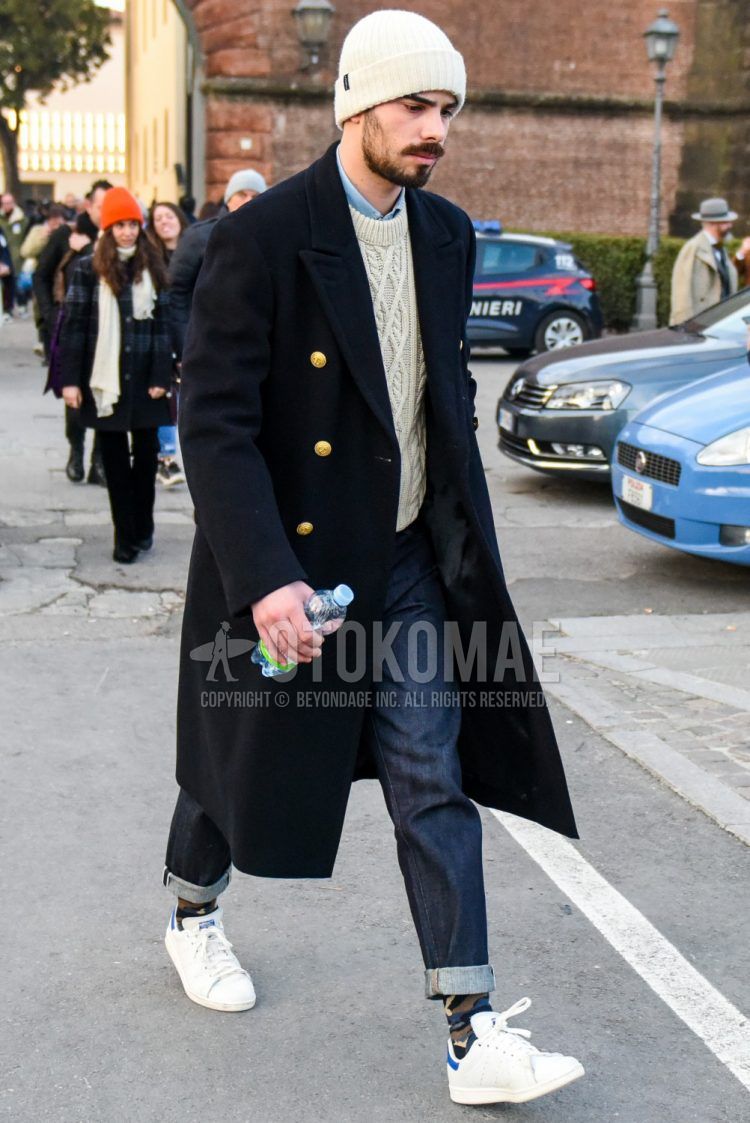 Men's coordinate and outfit with plain white knit cap, plain black chester coat, plain white sweater, plain light blue shirt, plain navy denim/jeans, olive green camouflage socks, and Adidas Stan Smith white low-cut sneakers.