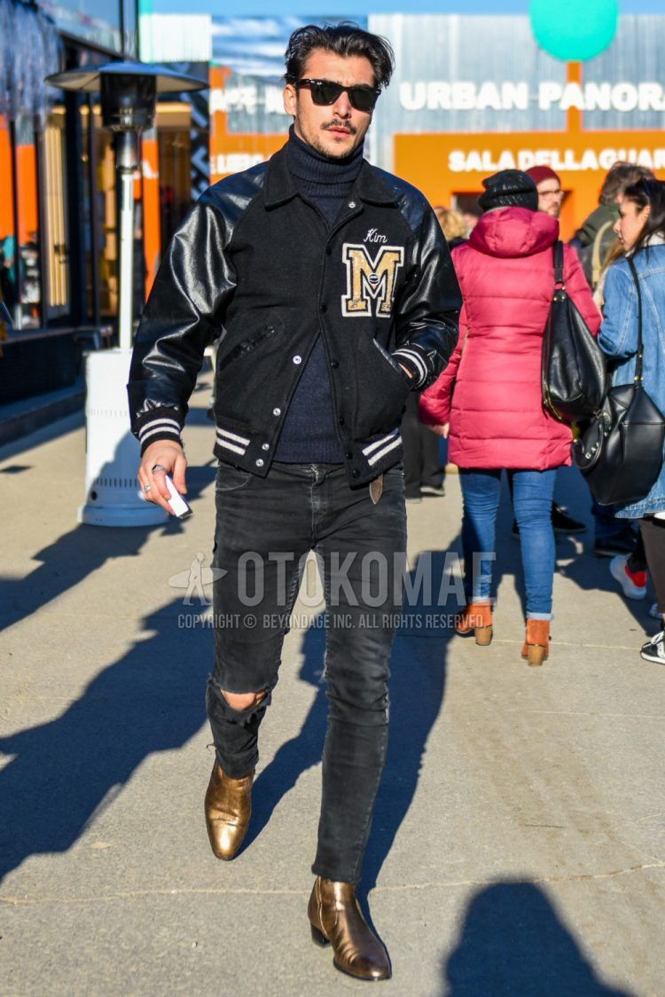 Men's coordinate and outfit with Ray-Ban Wayfarer plain black sunglasses, black lettered stadium jacket, dark gray plain turtleneck knit, plain black damaged jeans, and gold side gore boots.