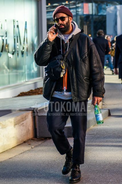 Men's coordinate and outfit with red solid knit cap, solid sunglasses, solid black leather jacket (not riders), solid gray hoodie, solid black cotton pants, black boots, and solid black body bag.