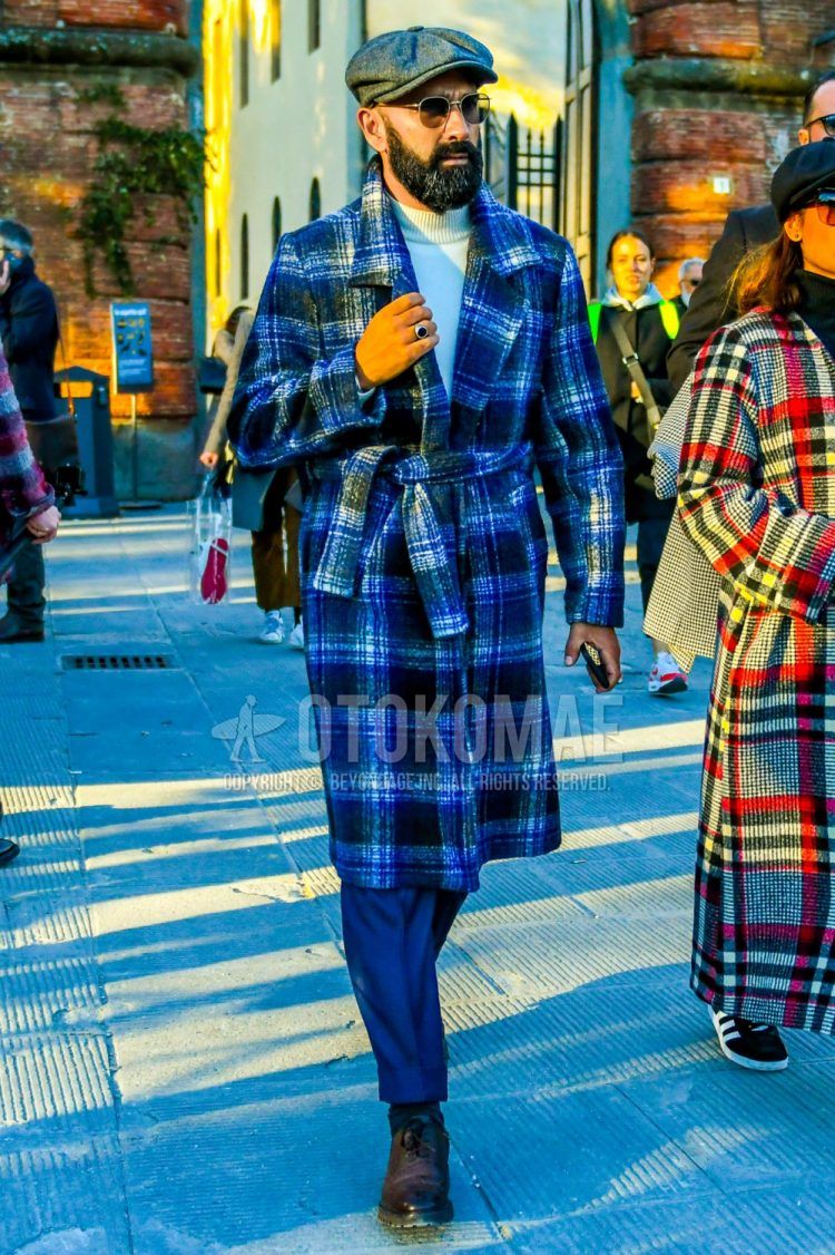 Men's coordinate and outfit with dark gray solid cap, blue checked belted coat, white solid turtleneck knit, blue solid slacks, dark gray solid socks, and purple wingtip leather shoes.