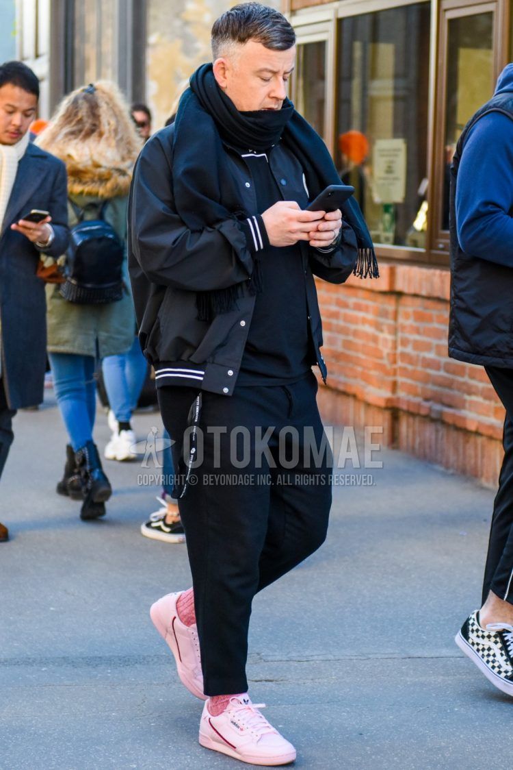Men's coordinate and outfit with plain black scarf/stall, plain black stadium jacket, plain black t-shirt from Acoldwall, plain black slacks, plain pink socks, pink low-cut sneakers from Adidas.