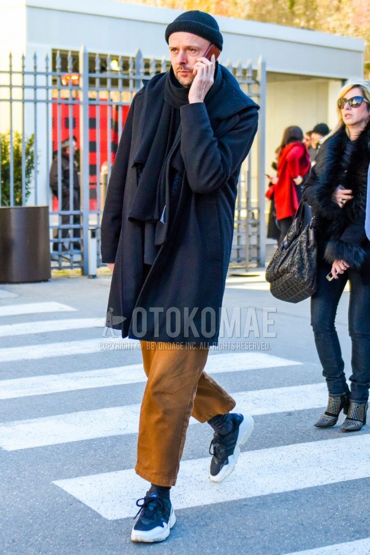 Men's outfit with dark gray solid knit cap, solid black scarf/stall, solid black hooded coat, solid brown chinos, solid brown wide leg pants, solid brown cropped pants, solid gray socks, adidas black low-cut sneakers. Outfit.