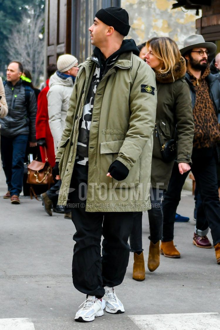 Men's coordinate and outfit with plain black knit cap, plain green down jacket, plain black hoodie, casual vest in white, black and gray camouflage, plain black wide pants, and Acoldwall Nike Air Bomero white low-cut sneakers.