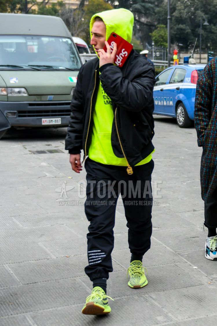 Men's coordinate and outfit with solid black MA-1, solid yellow hoodie, solid black jogger pants/ribbed pants, solid black socks, and Adidas yellow-cut sneakers.