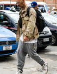 Men's coordinate and outfit with plain gold sunglasses, beige camouflage field jacket/hunting jacket, plain white t-shirt, plain gray sweatpants, Champion white high-cut sneakers, plain black backpack, and plain black body bag.