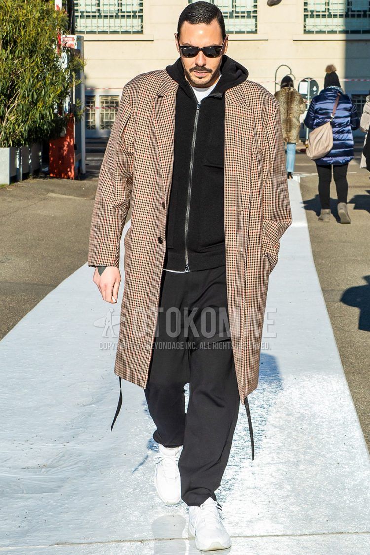 Men's coordinate and outfit with plain sunglasses, brown check chester coat, plain black hoodie, plain black wide-leg pants, and white low-cut sneakers.