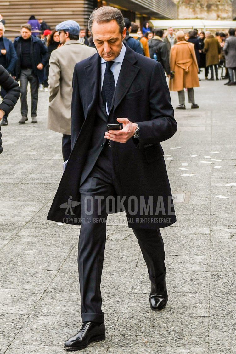 Men's coordinate and outfit with plain black chester coat, plain white shirt, black straight tip leather shoes, plain gray suit, and plain black tie.