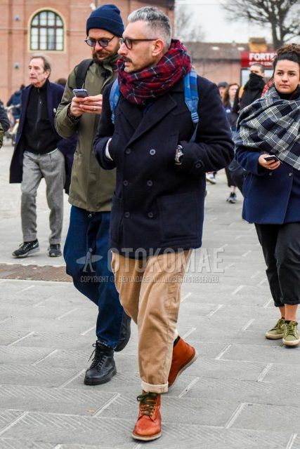 Men's coordinate and outfit with plain brown glasses, red/navy check scarf/stall, plain navy P-coat, solid beige winter pants (corduroy, velour) and brown boots.