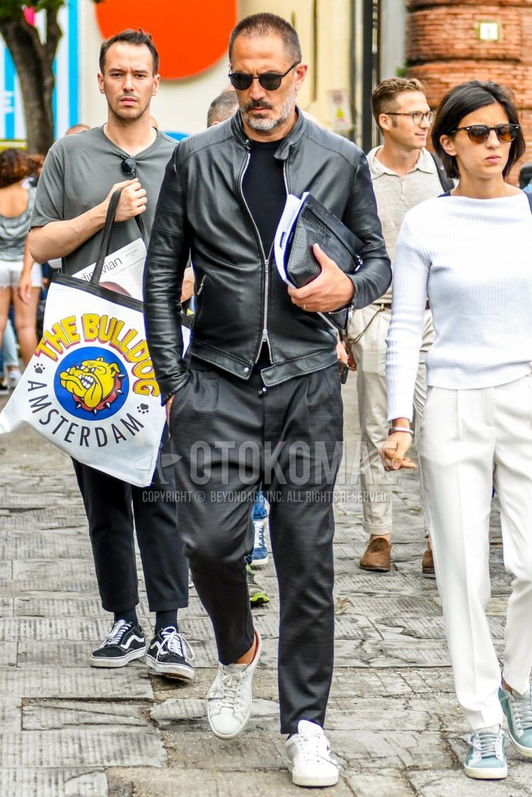 Men's coordinate and outfit with plain black sunglasses, plain black rider's jacket, plain black t-shirt, plain gray easy pants, and white low-cut sneakers.