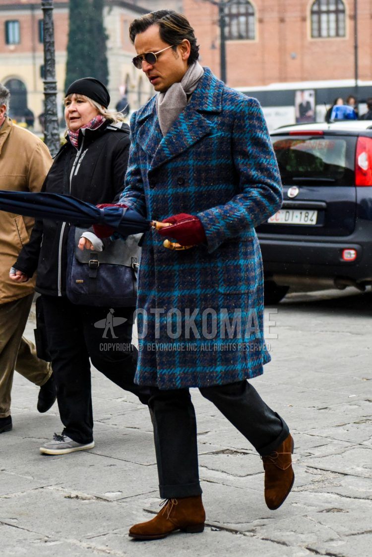 Men's coordinate and outfit with plain gold/black sunglasses, plain beige scarf/stall, blue checked Ulster coat, plain gray slacks, and suede brown chukka boots.