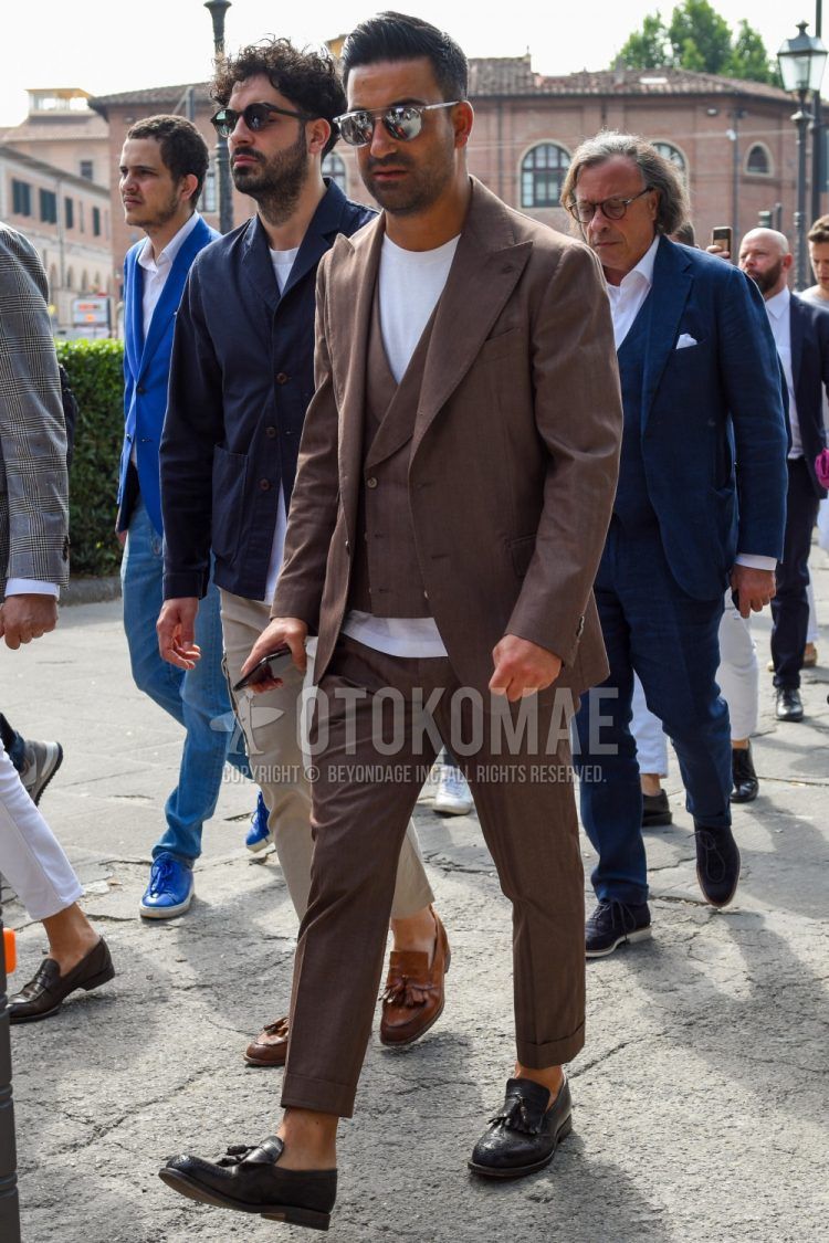 Men's coordinate and outfit with plain silver sunglasses, plain white T-shirt, black tassel loafer leather shoes, and plain beige three-piece suit.