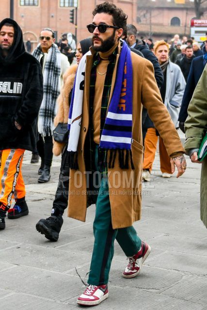 Men's coordinate and outfit with plain sunglasses, multi-colored graphic scarf/stall, plain beige chester coat, plain beige turtleneck knit, plain green sidelined pants, and white/red high-cut sneakers.