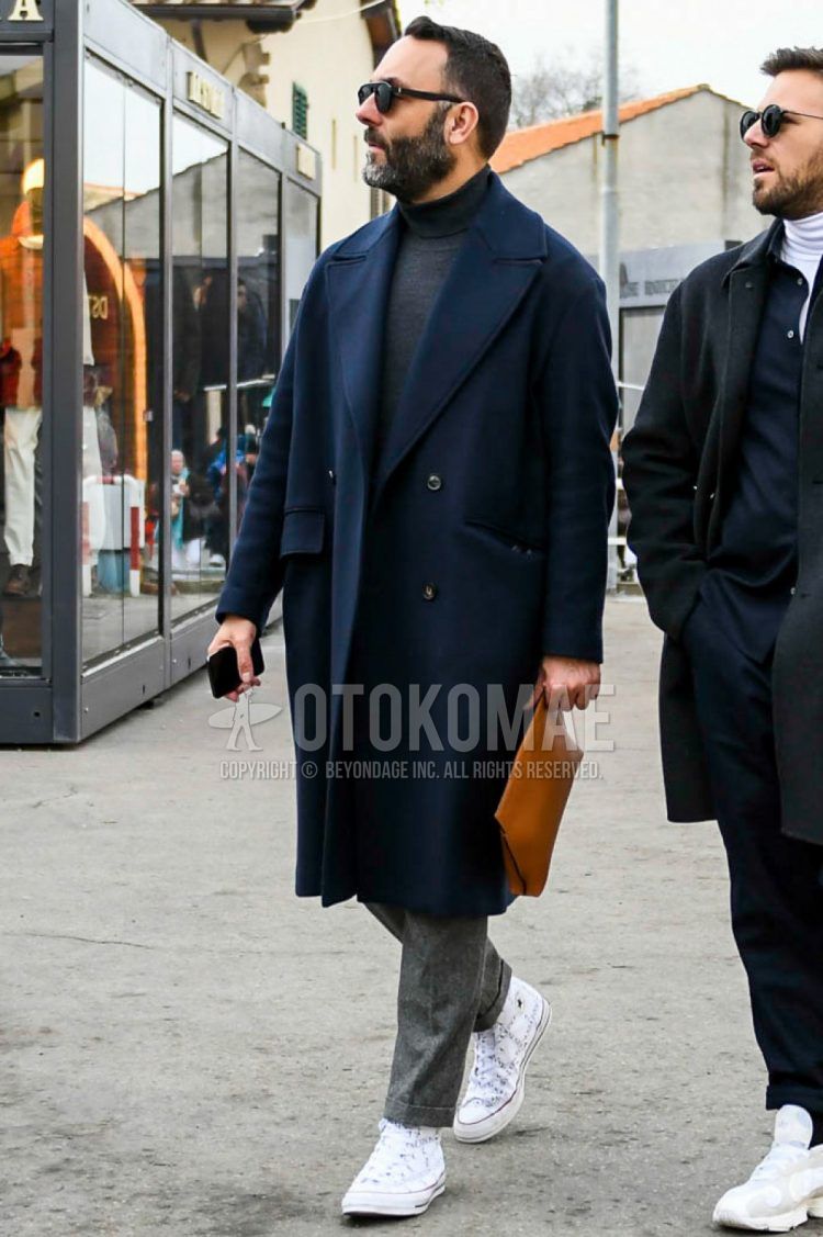 Winter men's outfit/coordination with plain black sunglasses, plain navy Ulster coat, plain dark gray turtleneck knit, plain gray slacks, Converse JW Anderson white high cut sneakers, plain brown clutch/second bag/drawstring bag.