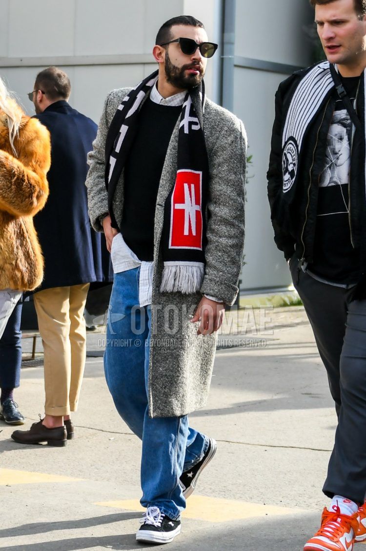 Winter men's coordinate and outfit with solid color sunglasses, black graphic scarf/stall, solid color gray chester coat, solid color black sweater, solid color white shirt, solid color blue denim/jeans, solid color blue wide leg pants, Converse One Star black low cut sneakers.