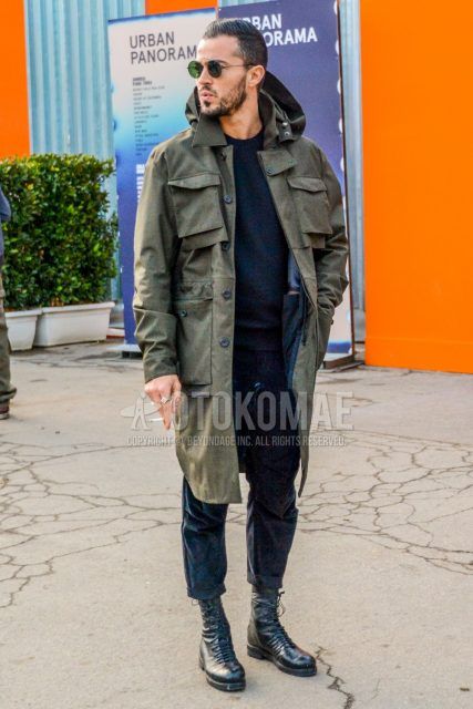 Men's coordinate and outfit with solid color sunglasses, olive green solid color hooded coat, solid color navy sweater, solid color navy bottoms, and black boots.