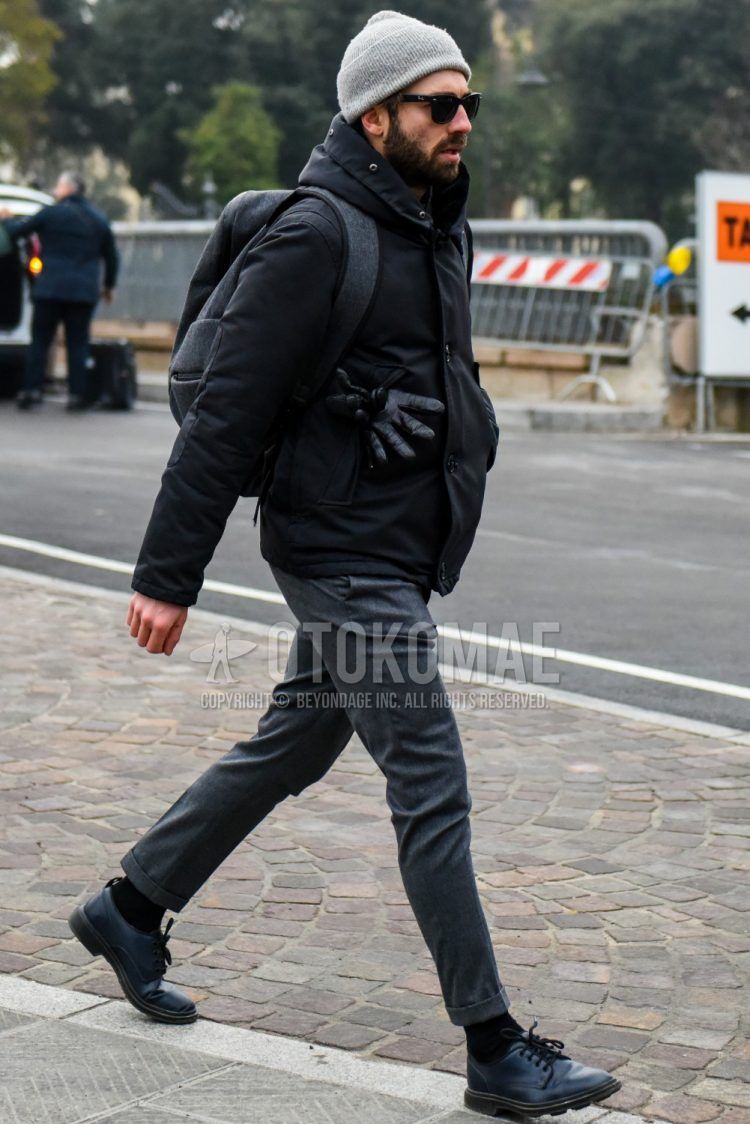 Men's coordinate and outfit with plain gray knit cap, plain Ray-Ban sunglasses, plain black down jacket, plain gray slacks, plain black socks, plain black toe leather shoes, and plain gray backpack.