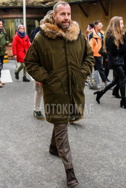 Men's coordinate and outfit with olive green solid color mod coat, brown solid color slacks, and brown boots.