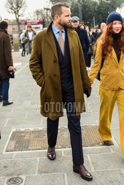 Men's coordinate and outfit with plain brown chester coat, plain light blue shirt, brown boots, black striped suit, and orange dot tie.