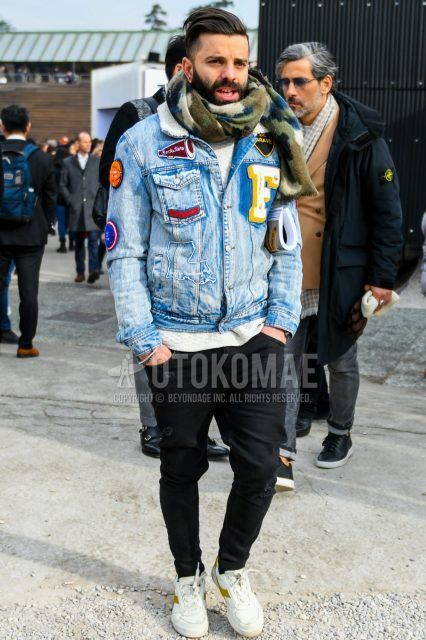 Men's coordinate and outfit with multi-colored stole scarf/stall, solid blue denim jacket, solid white sweater, solid black denim/jeans, and white low-cut Diadora sneakers.