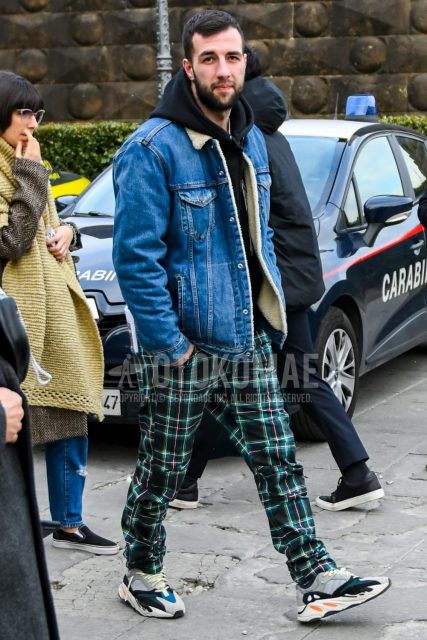 Men's coordinate and outfit with plain blue denim jacket, plain black hoodie, multi-colored checked cotton pants, and Yeezy Boost Wave Runner 700 gray low-cut sneakers.