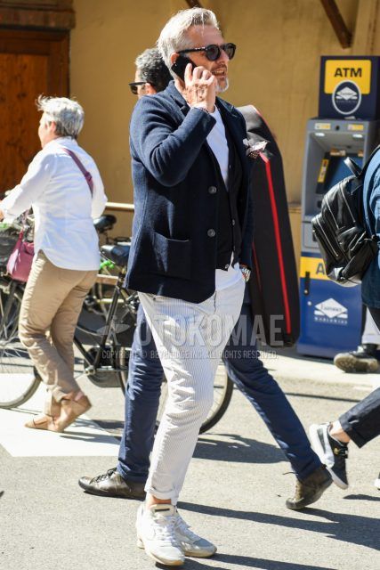 Men's coordinate and outfit with plain black sunglasses, plain black tailored jacket, plain black cardigan, plain white t-shirt, gray striped slacks, and Philip model white low-cut sneakers.