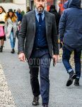 Men's coordinate and outfit with dark gray check tailored jacket, solid blue denim/chambray shirt, solid navy cardigan, solid dark gray slacks, multi-colored dotted socks, brown leather shoes, and solid navy knit tie.